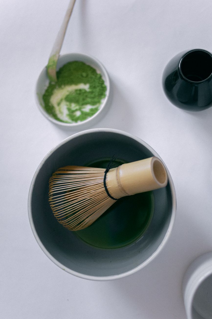 Handcrafted tea bowl and bamboo whisk on aged wood